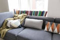 Cozy sofa with soft plaid and pillows near window in room Royalty Free Stock Photo