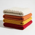Cozy stack of textured knit throws in warm autumnal colors for home decor isolated on white background Royalty Free Stock Photo