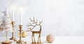 Cozy still life with burning candles, figure of deer and Christmas decorations on pastel light background. Christmas composition