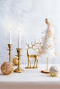 Cozy still life with burning candles, figure of deer and Christmas decorations on pastel light background. Christmas composition