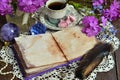 Cozy still life with open diary with blank pages, crystal, primrose flowers and cup of tea on table