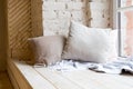 Cozy still life, warm woolen knitting decoration on windowsill against brick wall and window.boho style in living room