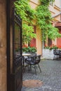 Cozy street cafe with iron fence in old town. Empty patio with outdoor furniture and red flowers. Royalty Free Stock Photo
