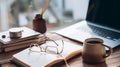 Cozy study desk with an open notebook, reading glasses, laptop, coffee, and aromatic diffuser. Royalty Free Stock Photo