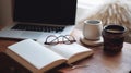 Cozy study desk setup with open notebook, elegant glasses, laptop, and warm beverages for learning. Royalty Free Stock Photo