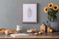 Cozy and stylish composition of creative dining room with mock up poter frame, wooden console, sunflower and personal accessories.