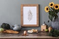 Cozy and stylish composition of creative dining room with mock up poter frame, wooden console, sunflowers and accessories. Royalty Free Stock Photo