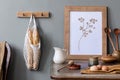 Cozy and stylish composition of creative dining room with mock up poter frame, wooden console, sunflowers and accessories.