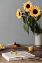 Cozy and stylish composition of creative dining room with wooden consola, sunflowers and personal accessories. Grey wall, details. Royalty Free Stock Photo