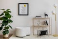 Cozy and stylish living room with mock up poster, white pouf, lamp, consola and personal accessories. Beige wall with carpet. Home