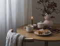 Cozy tea party - a cup of tea, muffins, cranberry branches, a bouquet in a vase, a notebook, a burning candle on a round wooden Royalty Free Stock Photo