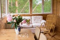 A cozy terrace with furniture - a wooden rocking chair, a sofa, peonies in a vase on the table and wicker chairs with a Royalty Free Stock Photo