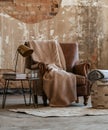 Cozy view of a beige blanket on a leather sofa in the middle of an undone room