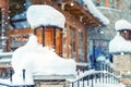 Cozy vintage street lamp with orange glass covered by snow and wooden rustic house on background outdoors at snowfall. Retro metal Royalty Free Stock Photo