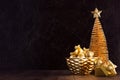 Cozy warm dark christmas background with golden star, christmas tree, balls, gift box, ribbons in modern black interior on brown. Royalty Free Stock Photo