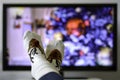 Cozy warm winter christmas socks with a reindeer. Person watching a christmas movie on the television