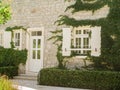 Cozy white stone house covered with ivy plant in village on sunny day Royalty Free Stock Photo