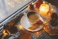 Cozy winter or autumn morning at home. Hot coffee with gold metallic spoon, warm blanket, garland and candle lights Royalty Free Stock Photo