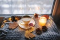 Cozy winter or autumn morning at home. Hot coffee with gold metallic spoon, warm blanket, garland and candle lights Royalty Free Stock Photo