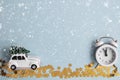 A cozy winter card with a Christmas car and a small alarm clock under the snow on a blue mint background. Royalty Free Stock Photo