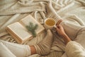 Cozy winter evening , warm woolen socks. Woman is lying feet up on white shaggy blanket and reading book. Cozy leisure scene Royalty Free Stock Photo