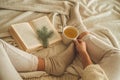 Cozy winter evening , warm woolen socks. Woman is lying feet up on white shaggy blanket and reading book. Cozy leisure scene Royalty Free Stock Photo