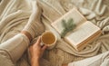 Cozy winter evening , warm woolen socks. Woman is lying feet up on white shaggy blanket and reading book. Cozy leisure scene Royalty Free Stock Photo