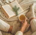 Cozy winter evening , warm woolen socks. Woman is lying feet up on white shaggy blanket and reading book. Cozy leisure scene Royalty Free Stock Photo