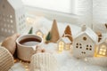 Cozy winter. Hands in sweater holding stylish cup of tea with modern christmas decoration, pine cone, wooden star and tree, golden Royalty Free Stock Photo