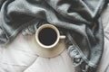 Cozy winter home background, cup of hot coffee with marshmallow, warm knitted sweater on white bed background, vintage tone.