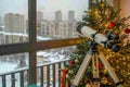 Cozy Winter Interior with Christmas Tree and Telescope Overlooking Snowy Cityscape from Urban Apartment Royalty Free Stock Photo