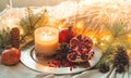 Cozy winter morning at home with fruits. Pomegranate in a winter composition, Christmas trees, cones in a jar on the background