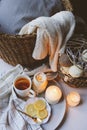 Cozy winter morning at home. Hot tea with lemon, candles, knitted sweaters in basket and modern metallic interior details Royalty Free Stock Photo