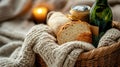 Cozy winter picnic basket with bread, wine, and candlelight on knitted blanket Royalty Free Stock Photo