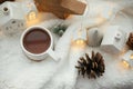 Cozy winter still life. Stylish cup of tea with modern christmas decoration, pine cone, wooden star and tree, golden light on soft Royalty Free Stock Photo