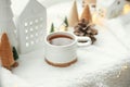 Cozy winter still life. Stylish cup of tea with modern christmas decoration, pine cone, wooden star and tree, golden lights on Royalty Free Stock Photo
