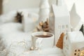 Cozy winter still life. Stylish cup of tea with modern christmas decoration, pine cone, wooden star and tree, golden lights on Royalty Free Stock Photo