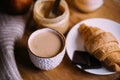 Cozy winter weekend breakfast, coffee and croissant on wooden tray