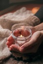 Cozy winter weekend at home. Hands holding candle. Hygge concept. Still life details of living room Royalty Free Stock Photo