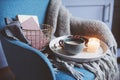 Cozy winter weekend at home. Morning with coffee or cocoa, books, warm knitted blanket and nordic style chair. Hygge concept. Royalty Free Stock Photo