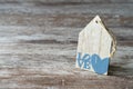 Cozy wooden background, with a piece of wood in the shape of a house, a heart and the word written love, love concept, for
