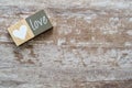 Cozy wooden background in white and grayish tones, with a white wooden heart and the word love on another piece of wood. Love