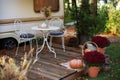 Cozy wooden house porch with garden furniture. Decor summer yard. Interior cozy patio with chrysanthemums in pots. Table and chair