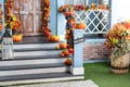 Cozy wooden porch of the house with pumpkins in fall time. Halloween design home with yellow fall leaves and lanterns. Royalty Free Stock Photo