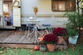 Cozy wooden RV house porch with garden furniture. Decor summer yard. Interior cozy patio with chrysanthemums in pots. Table and ch Royalty Free Stock Photo