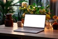 Cozy workplace with a laptop with an empty screen, indoor flowers on a wooden table