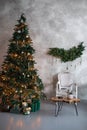 Cozy xmas loft interior room with armchair and Christmas tree with lights glowing garlands. Christmas tree decorated with toys, ba Royalty Free Stock Photo