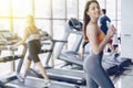 Young attractive girl in the gym drinking water on the background of treadmills Royalty Free Stock Photo