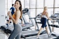 Young attractive girl in the gym drinking water on the background of treadmills Royalty Free Stock Photo