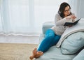 Cozying up with a good page turner. a young woman relaxing on the sofa and reading a book at home. Royalty Free Stock Photo